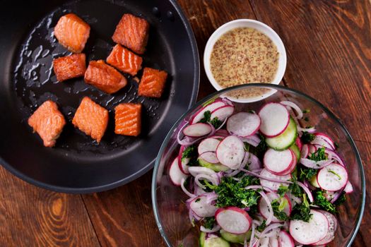 Ingredients. Broiled salmon with radish and spinach, served on wooden table. View from above, top studio shot