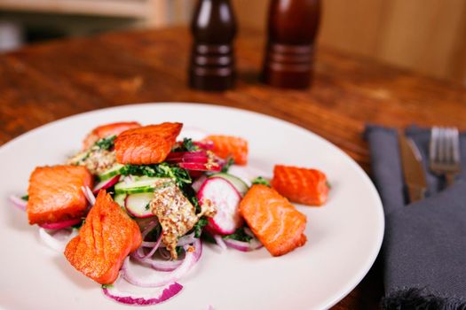 Red fish salmon with radish and spinach, served on white plate on wooden table. rustick style. View from above, top studio shot