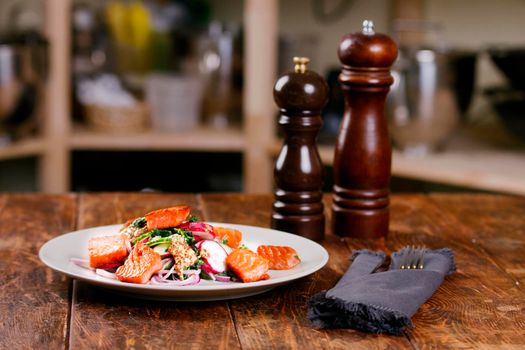 Red fish salmon with radish and spinach, served on white plate on wooden table. rustick style. View from above, top studio shot