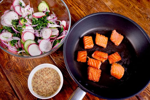 Ingredients. Broiled salmon with radish and spinach, served on wooden table. View from above, top studio shot