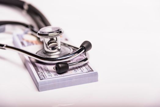 Medical concept - stethoscope over the dollar bills isolated on white background