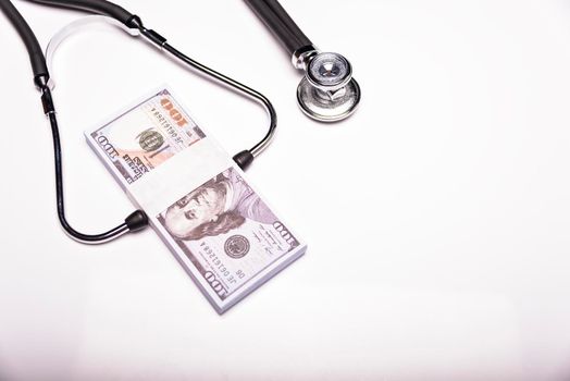 Medical concept - stethoscope over the dollar bills isolated on white background