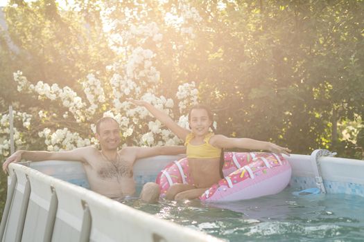 Little girl and happy dad having fun together in outdoors swimming pool