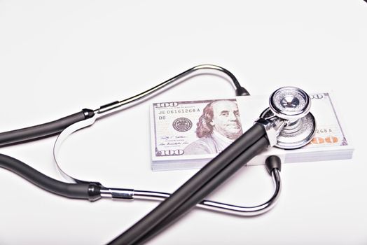 Medical concept - stethoscope over the dollar bills isolated on white background
