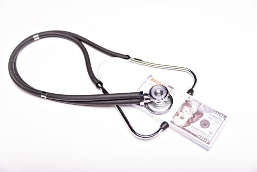 Medical concept - stethoscope over the dollar bills isolated on white background