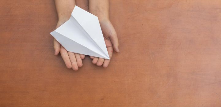 Child's Dream. Child's hand launching white paper airplane.