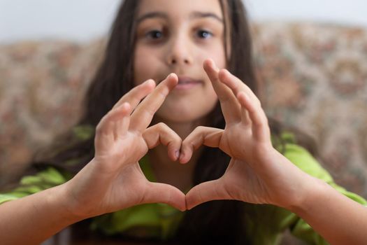 A cute Caucasian child holds a palm in the shape of a heart