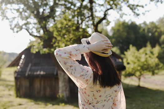romantic portrait of a young woman in straw hat and beautiful dress in the countryside in summer.