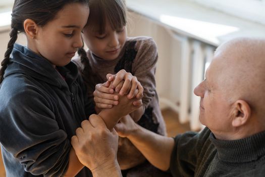 hands of grandfather and granddaughter with prayer.