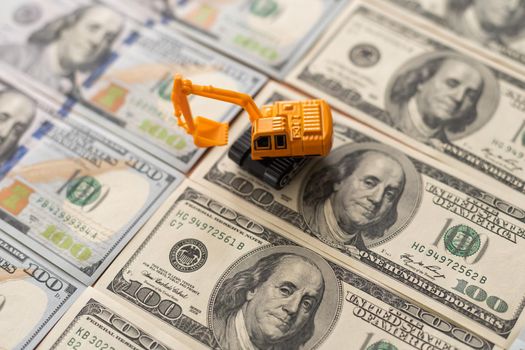 one hundred dollar bills and a toy excavator.