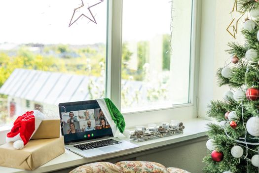 A happy family with a child is celebrating Christmas with their friends on video call using webcam. Family greeting their relatives on Christmas eve online. New normal virtual event