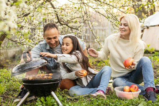 smiling parent grilling meat with daughter on camping.