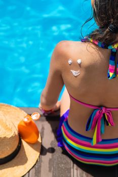 Child near the pool smears sunscreen. Selection focus. Kid.