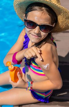 Child near the pool smears sunscreen. Selection focus. Kid.