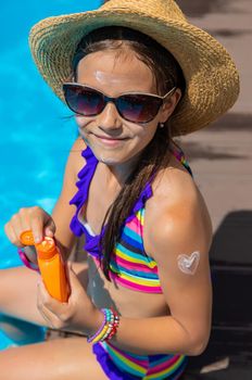 Child near the pool smears sunscreen. Selection focus. Kid.