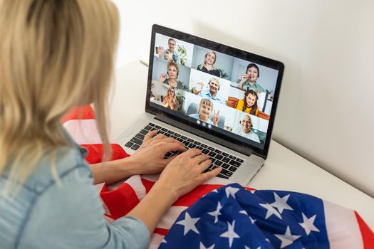 woman holding usa flag and video by laptop.