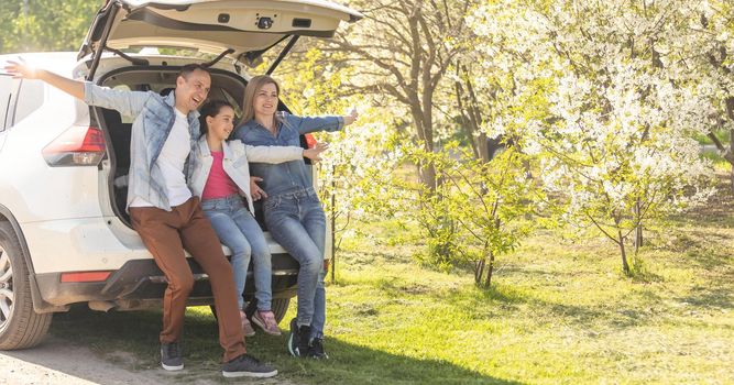 Family with kids sitting in car trunk.