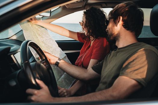 Side View of Man and Woman Sitting in Car and Checking Map, Young Couple Enjoying Road Trip