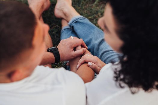 Close Up Back View of Man and Woman Holding by Hands Sitting on Ground Outdoors, Middle Aged Couple in Love