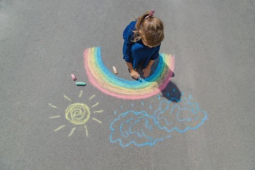 child draws with chalk on the pavement. Selective focus. nature.