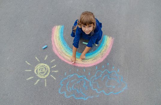 child draws with chalk on the pavement. Selective focus.