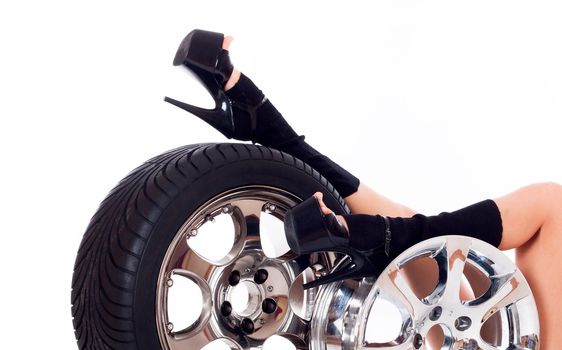 Young sexy girl lying near the car wheel and disk, isolated on white
