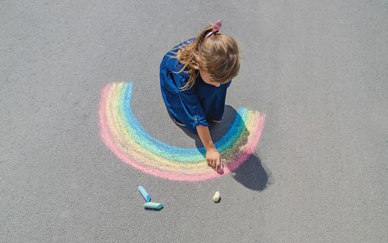 child draws with chalk on the pavement. Selective focus.