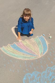 child draws with chalk on the pavement. Selective focus.