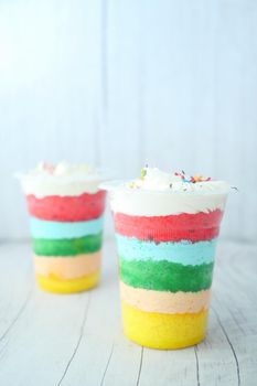 rainbow color cake in a plastic container on table ,