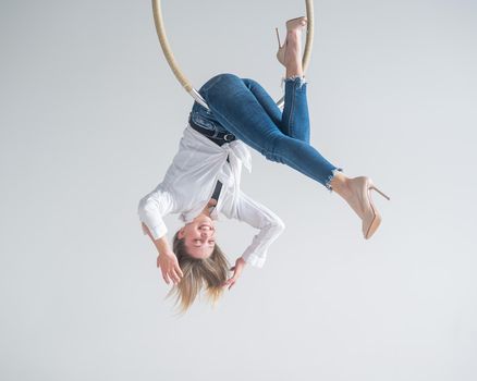 Caucasian woman in casual clothes on an aerial hoop