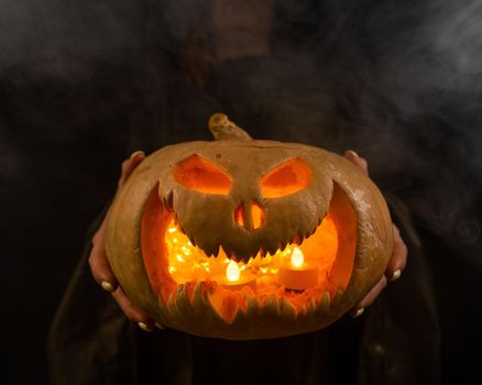 The witch is holding a pumpkin jack about a lantern glowing in the dark. Halloween