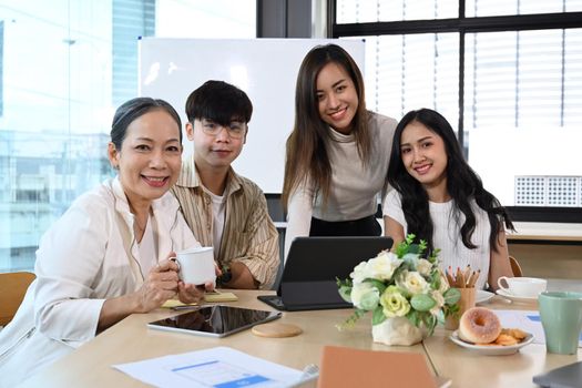 Team of professionals business people sitting in meeting room and smiling at camera.