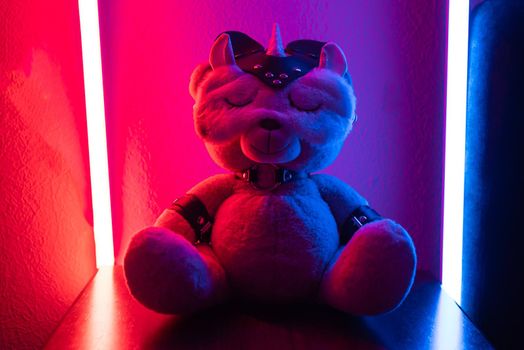 the toy teddy bear dressed in leather straps and a mask, an accessory for BDSM games in a sleep mask