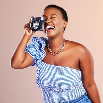 Studio shot of a beautiful young woman using a camera against a oink background.