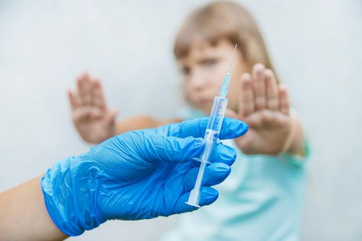 The doctor gives the child an injection in the arm. Selective focus.