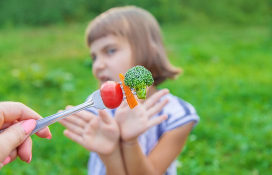 child eats vegetables broccoli and carrots. Selective focus.