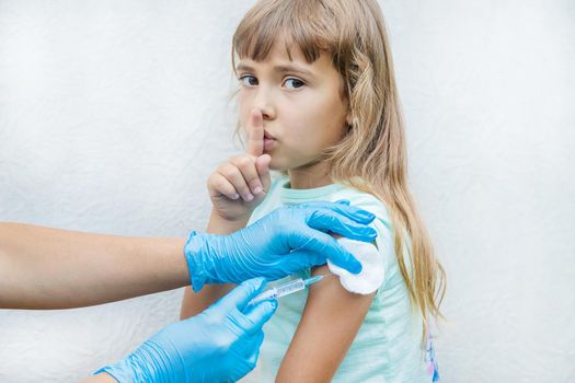 The doctor gives the child an injection in the arm. Selective focus.