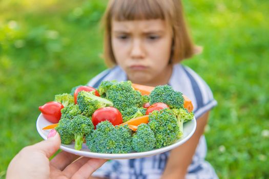 child eats vegetables broccoli and carrots. Selective focus.