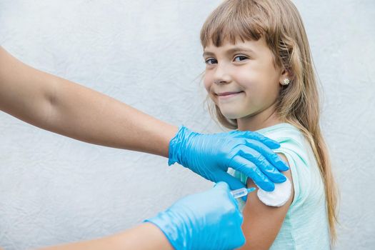 The doctor gives the child an injection in the arm. Selective focus.