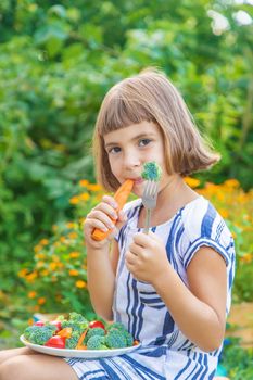 child eats vegetables broccoli and carrots. Selective focus.