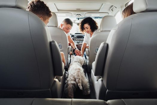 Four Members Family Traveling by Minivan Car, Mother and Father with Two Teenage Children and Pet West Highland White Terrier Dog on Weekend Road Trip