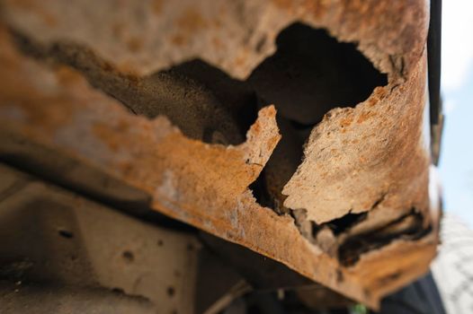 Rusty car body damaged by corrosion with hole on threshold.