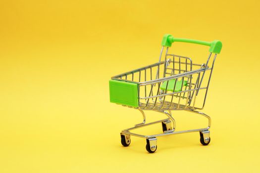 Shopping concept. New empty shopping cart on yellow background