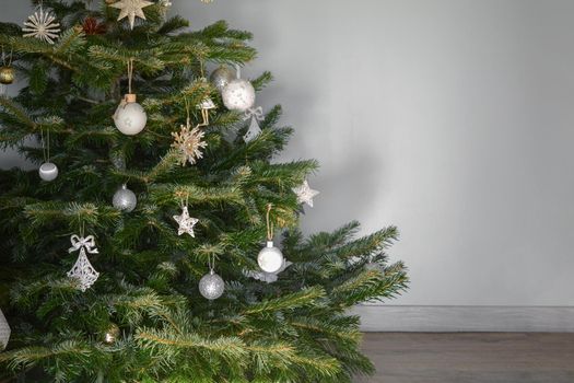 Christmas tree decorated with toys against a gray wall