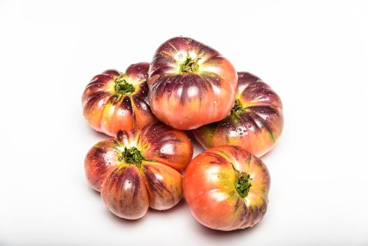 Several tomatoes of the tiger variety on a white background