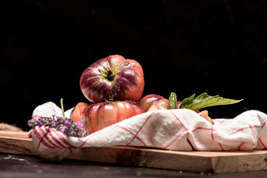 Fresh tomatoes in a plate on a dark background. Harvesting tomatoes. Top view