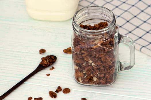 chocolate granola in a glass mug stands on a wooden background. Dry oatmeal in a jar. Healthy breakfast concept. High quality photo