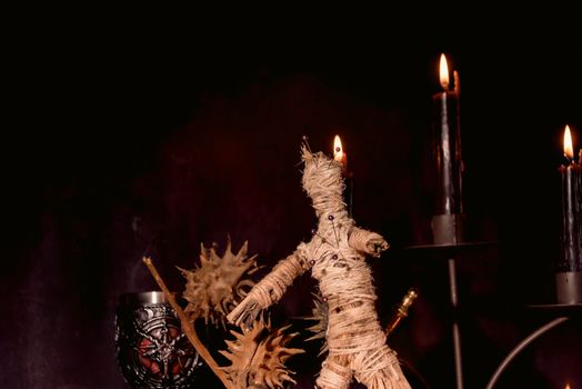 Scary voodoo doll with black candles. Mystic background with ritual esoteric objects, occult and halloween concept