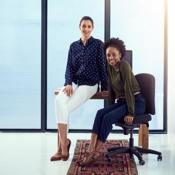 Portrait of two young designers at a work station in front of a window.