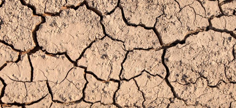 Cracked earth in dry river bed during times of drought. Texture of dry cracked soil. High quality photo